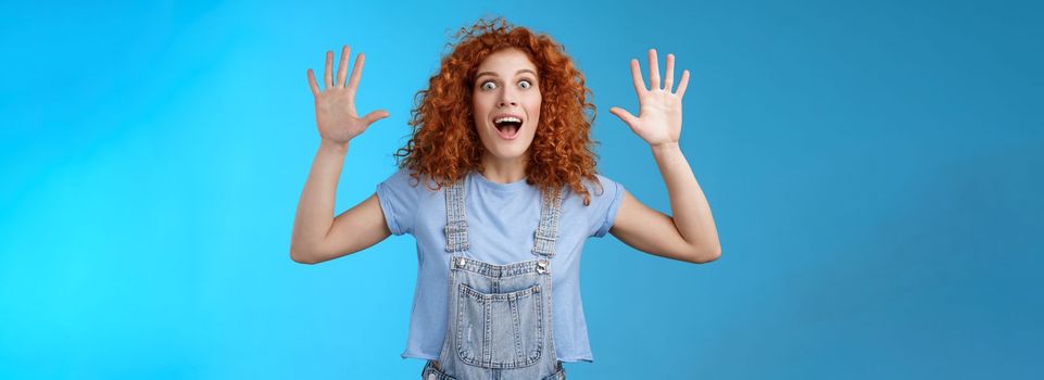 Lifestyle. Excited crazy playful funny redhead curly emotive girl yelling carefree raise hands surrender up open mouth fool around smiling broadly stare camera joyful express wild daring emotions.