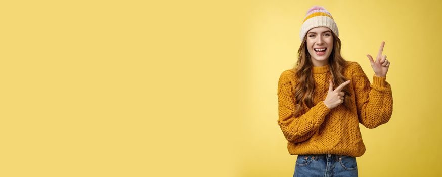 Carefree friendly nice flirty stylish woman wearing sweater hat laughing joyfully enjoying funny company joking pointing upper right corner index fingers delighted, showing cool promotion.