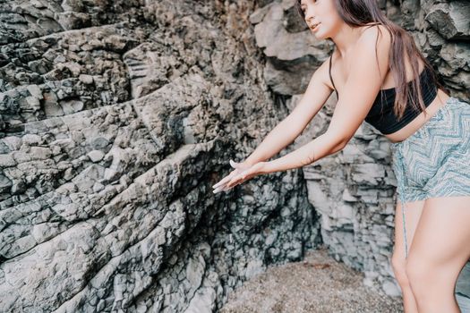 A girl climbs a rock. The athlete trains in nature. Woman overcomes difficult climbing route. Extreme hobby. Tourist woman rock climber hiking on mountains rocks over beautiful sea coast
