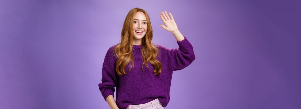 High five mate, hello. Portrait of friendly and excited charming kind redhead girl in sweater raising hand and waving in hi gesture, greeting best friend and smiling broadly as pleased meet.