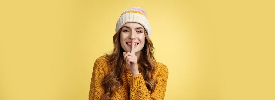 Shush listen. Portrait attractive flirty smiling devious cute european woman have secret showing shh gesture index finger pressed lips sharing interesting rumor, standing happily yellow background.