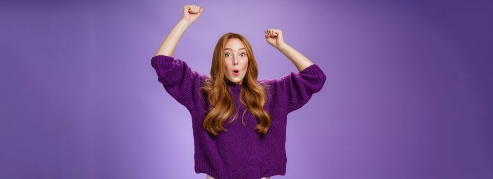 Excited and thrilled woman reacting to unexpected goal raising hands in wave gesture folding lips inhaling breath to scream yes and wow being impressed, triumphing from success and good news.
