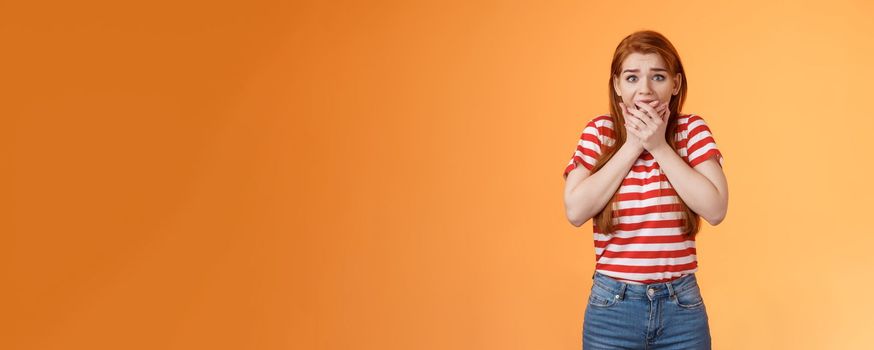 Scared speechless innocent female victim losing speech, press hands mouth shocked terrified stare camera frightened, trembling from fear, see someone commiting crime, insecure orange background.