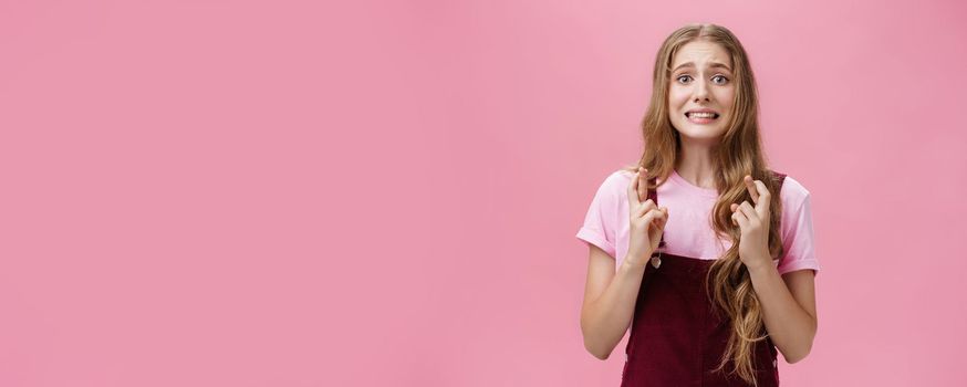 Woman overreacting feeling worried for important result waiting nervously crossing fingers for good luck clenching teeth and frowning looking concerned at camera, praying hopefully for wish come true.