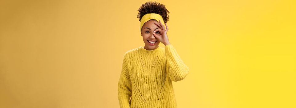 Charming tender feminine african-american girlfriend show circle on eye ok okay gesture look lucky happily smiling satisfied impressed waiting excitement travel friends, yellow background.