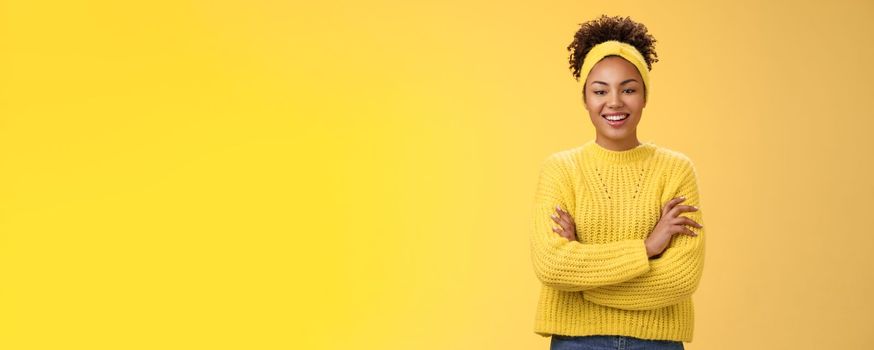 Serious powerful good-looking smiling african-american female femenist blogger cross hands chest confident pose grinning delighted enjoying watching working process, standing yellow background.