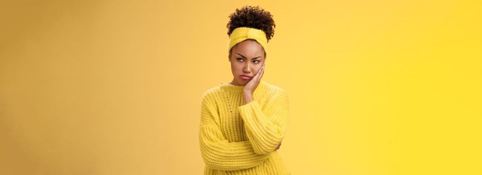 Offended gloomy grumpy pouting young african-american. girlfriend feel irritated jealous frowning bothered sulking look away insulted unwilling talk somebody lean hand head standing yellow background.