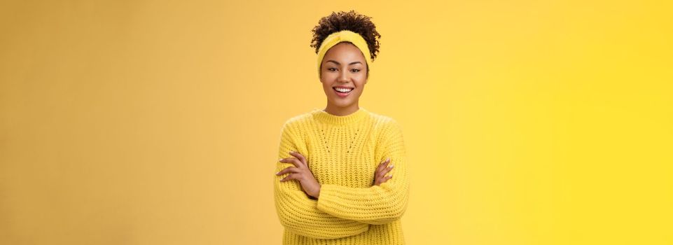 Serious powerful good-looking smiling african-american female femenist blogger cross hands chest confident pose grinning delighted enjoying watching working process, standing yellow background.