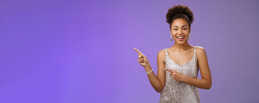 Good-looking elegant confident african-american female club owner pointing upper left wear stylish evening night dress smiling assured suggest comfortable place stay enjoy party, blue background.