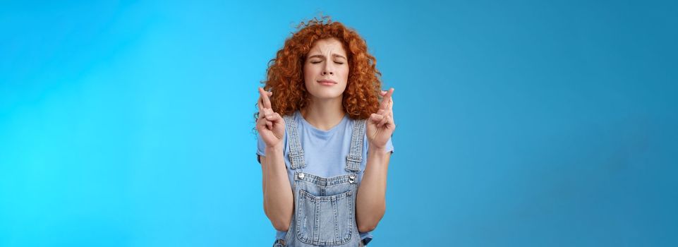 Lifestyle. Intense nervous attractive redhead curly-haired hopeful focused girl praying supplicating asking god make dream come true cross fingers good luck anticipating important news wanna wish fulfill.