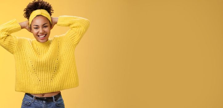 Attractive lucky optimistic african-american woman having fun lay back hands behind head smiling laughing happily enjoying perfect day-off work relaxing spend leisure fun, yellow background.