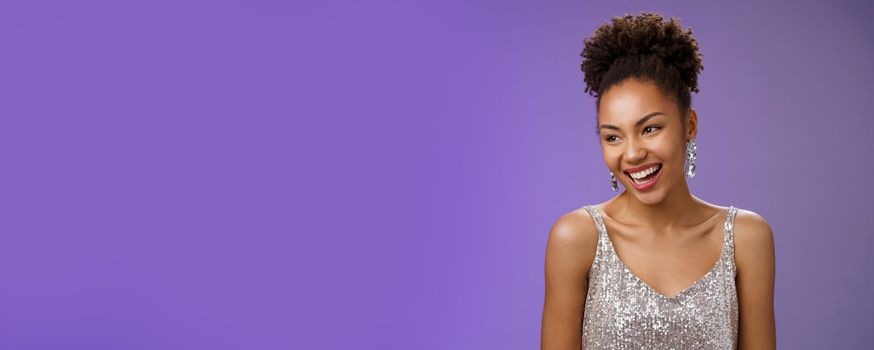 Close-up talkative elegant glamour african-american young girl host party wearing luxurious fashionable silver dress talking laughing happily during conversation standing blue background.