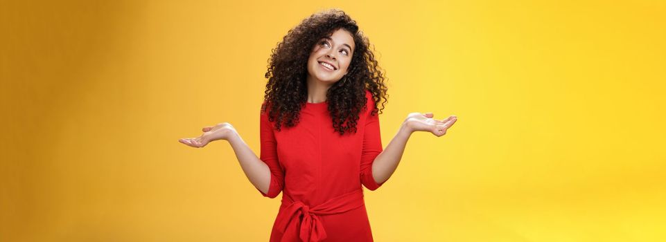 Girl feeling clueless and silly, being unbothered with anything, shrugging dreamy and indifferent, smiling carefree as looking dreamy at upper right corner, spread hands sideways in uncertain gesture.