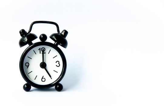 Black alarm clock pointing at 5 o'clock with customizable space for text on white background. Copy space.