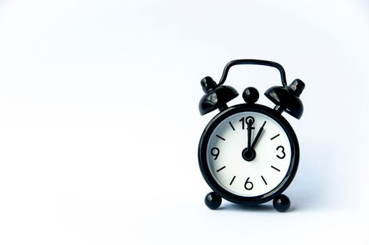 Black alarm clock pointing at 1 o'clock with customizable space for text on white background. Copy space.