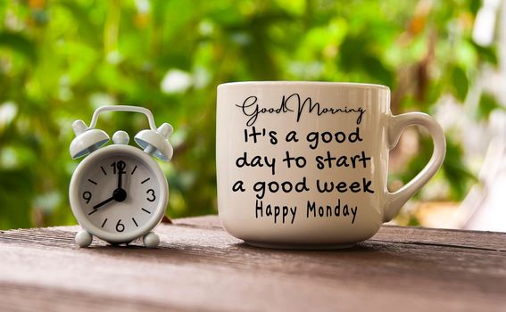 Good Morning, it is a a good day to start a good week text on coffee cup with alarm clock pointing at 8am.