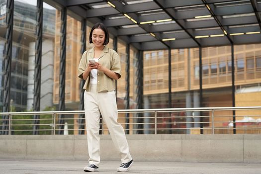 Portrait of asian female model with telephone. Young korean girl holding smartphone on street, using telephone.