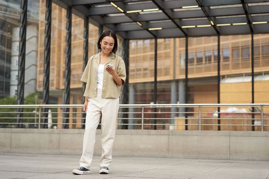 Portrait of asian female model with telephone. Young korean girl holding smartphone on street, using telephone.