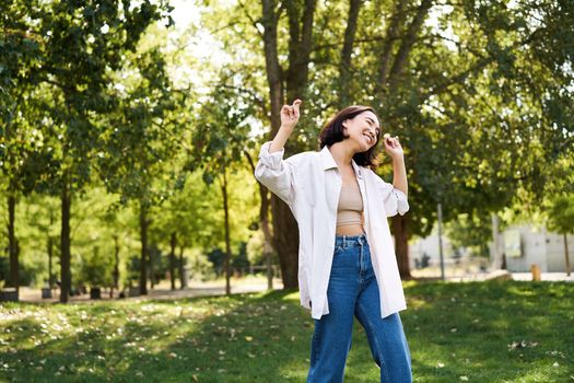 Portrait of happy girl dancing and looking happy, posing in park, enjoying herself, walking alone, feeling freedom and excitement.