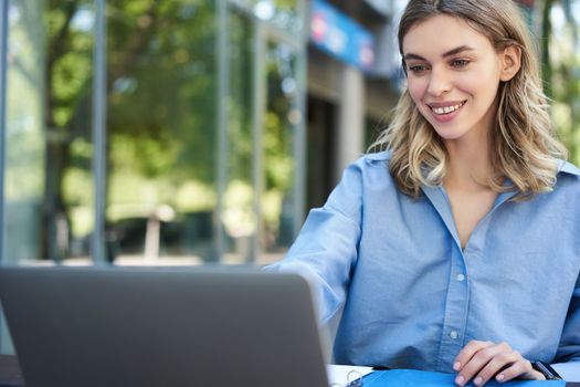 Portrait of businesswoman working with laptop. Corporate woman using computer outdoors, attend video chat meeting while sitting outside office.