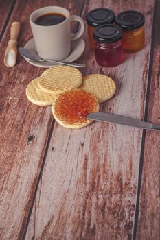 cookies with jam and coffee cup on a wooden table