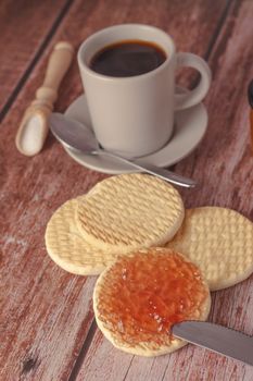 cookies with jam and coffee cup on a wooden table