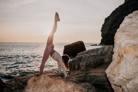 Young woman with black hair, fitness instructor in pink sports leggings and tops, doing pilates on yoga mat with magic pilates ring by the sea on the beach. Female fitness daily yoga concept