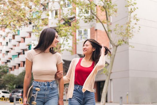 couple of women strolling happy arm in arm through the city, concept of female friendship and love