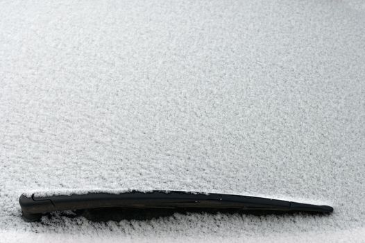 Snowy windshield on a car with wipers. Winter concept for traffic and road safety.