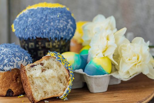 Easter cakes in the colors of the flag of Ukraine, yellow and blue in a cardboard stand with eggs, Easter eggs. place for text. selective focus.