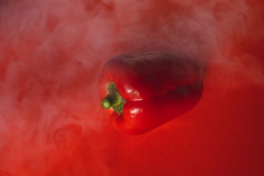 SWEET, fresh RED PEPPER ON A RED BACKGROUND WITH A LIGHT SMOKE.