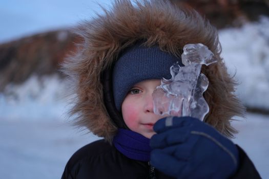 A boy with rosy cheeks looks through the transparent Baikal ice on Olkhon Island