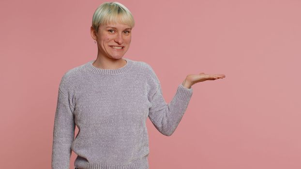 Lovely woman with short green hair showing thumbs up and pointing empty place, advertising area for commercial text, copy space for goods promotion. Young girl on pink background. Lgbt lesbian people