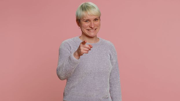 I choose you. Young woman with short hair smiling excitedly, pointing to camera, choosing lucky lottery winner, indicating to awesome you. Girl isolated on pink background. Lgbt gay lesbian people