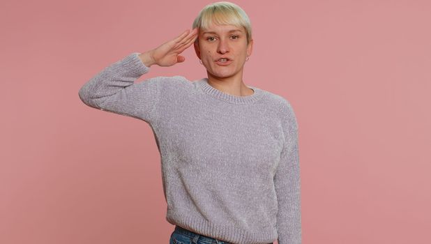 Yes sir. Subordinate responsible serious woman giving salute listening to order as if soldier following discipline obeying expressing confidence. Young girl on pink background. Lgbt gay lesbian people
