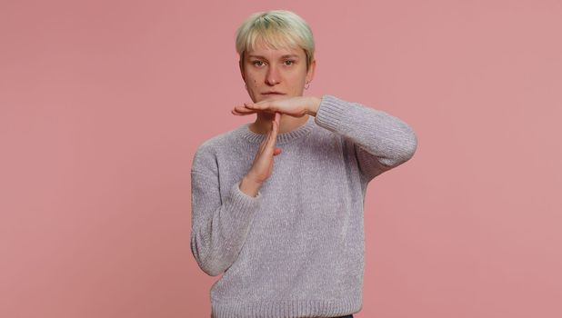 Tired serious upset millennial woman with short hair showing time out gesture, limit or stop sign, no pressure, i need more time. Young girl isolated on pink studio background. Lgbt gay lesbian people