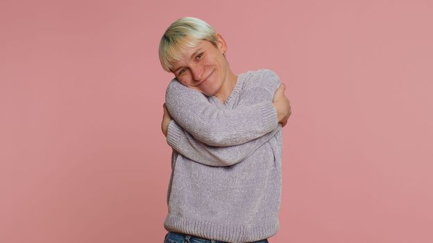Come to me, I want to embrace you. Woman with short hair spread hands and give hug to you. Pleasant expression, love feelings. Young girl isolated on pink studio background. Lgbt gay lesbian people