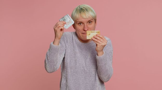 Woman showing plastic credit bank card advertising transferring money, taking loan, purchases online shopping sale discount, internet order delivery purchase. Young girl isolated on pink background