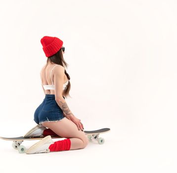 sexy girl in a fashionable red hat sitting on a longboard on a white background copy paste