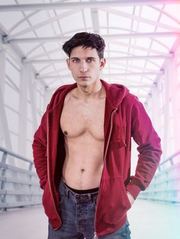 Athletic young man undressing, with open red hoodie sweater on naked muscle torso