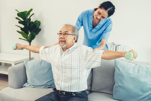 Contented senior patient doing physical therapy with the help of his caregiver. Senior physical therapy, physiotherapy treatment, nursing home for the elderly