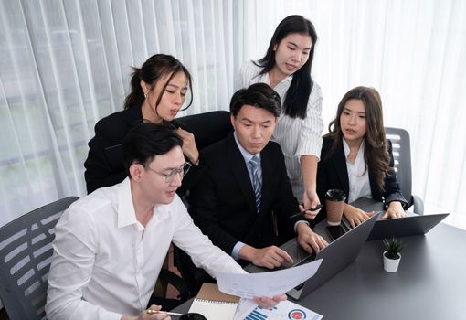 Harmony in office concept as business people analyzing dashboard paper together in workplace. Young colleagues give ideas at manager desk for discussion or strategy planning about project.