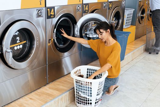 Asian people using qualified coin operated laundry machine in the public room to wash their cloths. Concept of a self service commercial laundry and drying machine in a public room.