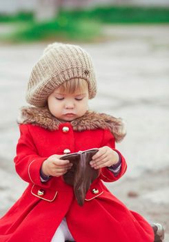 charming baby in a red coat looks into wallet.
