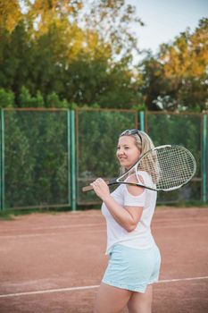 gorgeous blonde in blue shorts standing with a tennis racket on a Sportsground