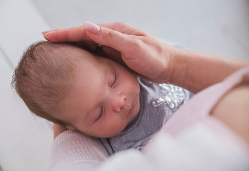 mother holds baby in her arms and stroking his head.