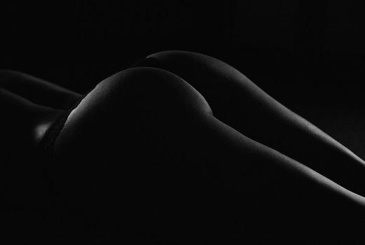 dark silhouette of slim female buttocks in underpants.