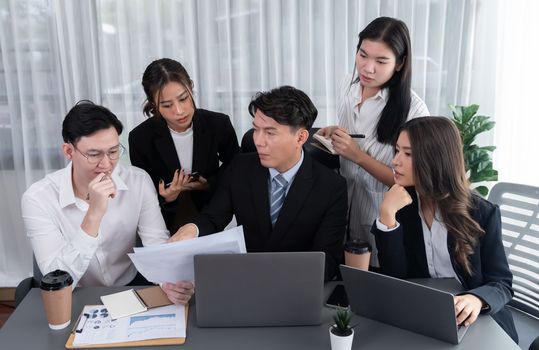 Harmony in office concept as business people analyzing dashboard paper together in workplace. Young colleagues give ideas at manager desk for discussion or strategy planning about project.