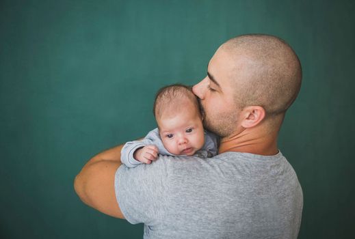 Young father with short hair kisses his newborn daughter.