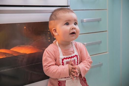 Adorable newborn girl in an apron prepares pies.